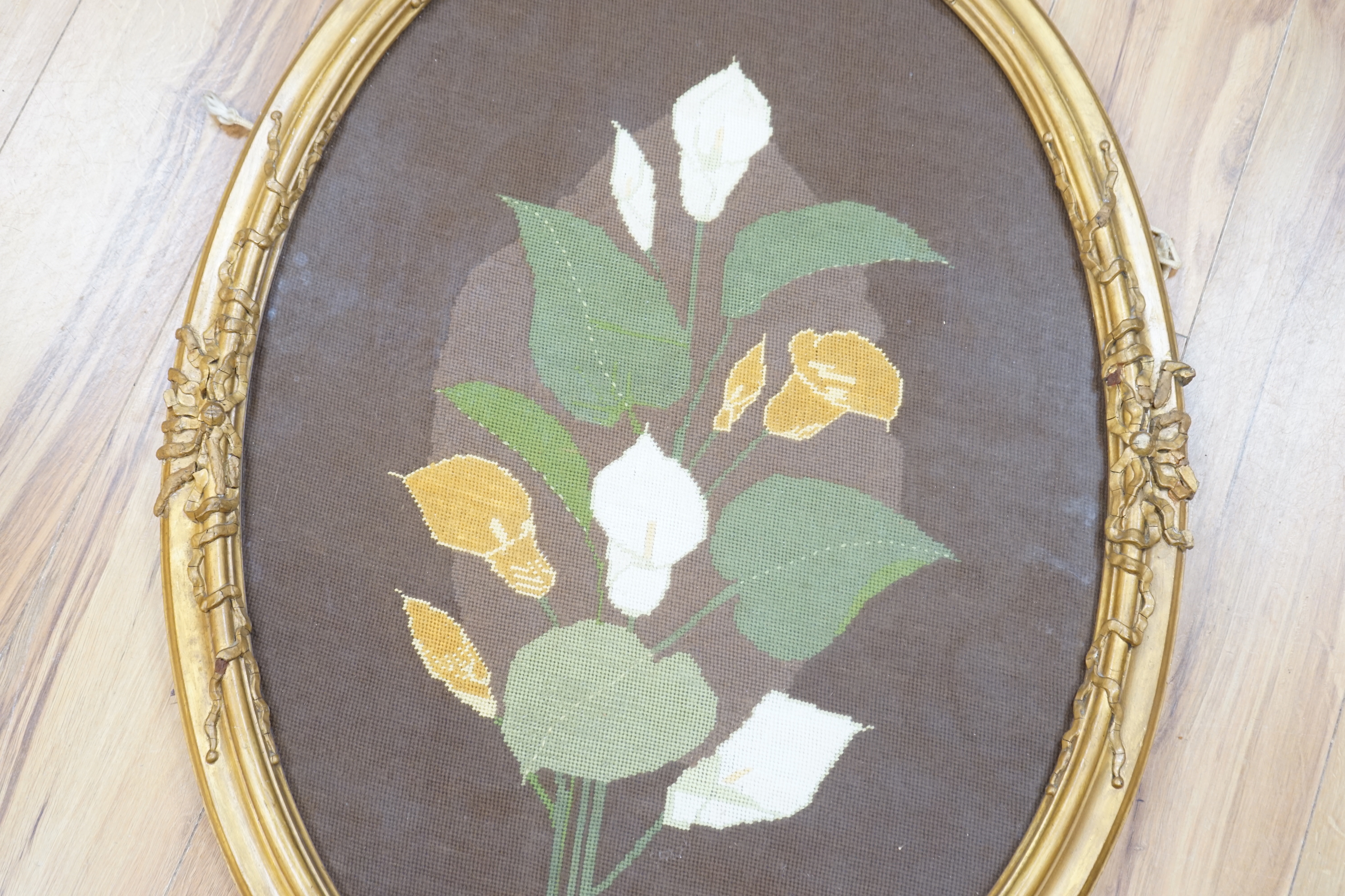 An oval framed cross stitch embroidery of a lily, indistinctly signed and dated, 80cm x 54cm